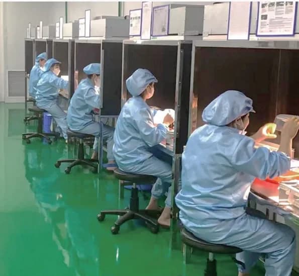 Row of visual inspection booths with cleanroom operators